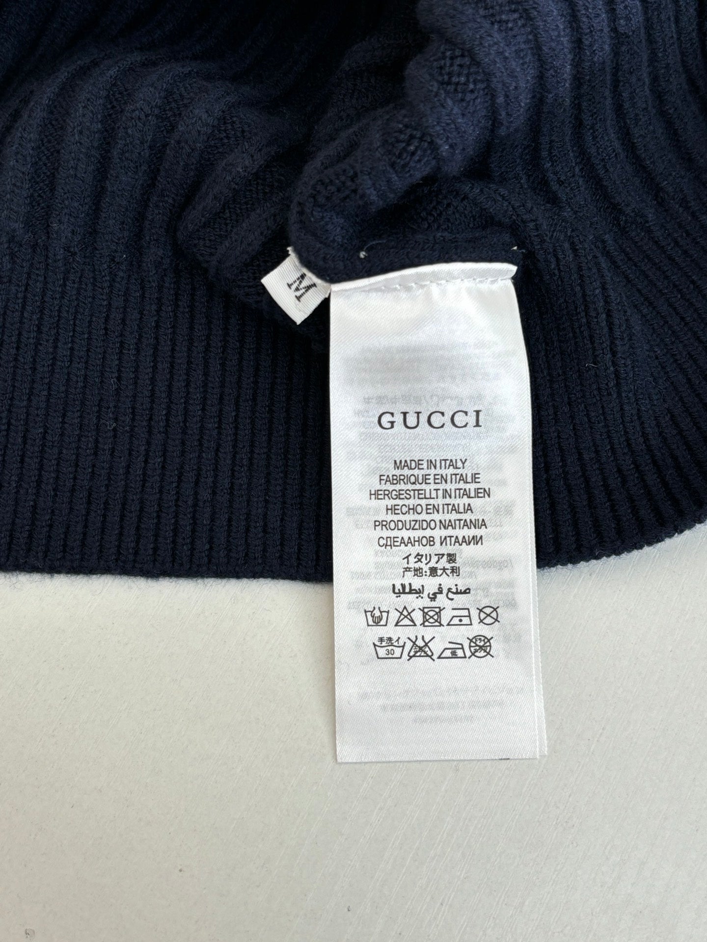 Interior care label on navy knit sweater, Gucci and made in Italy