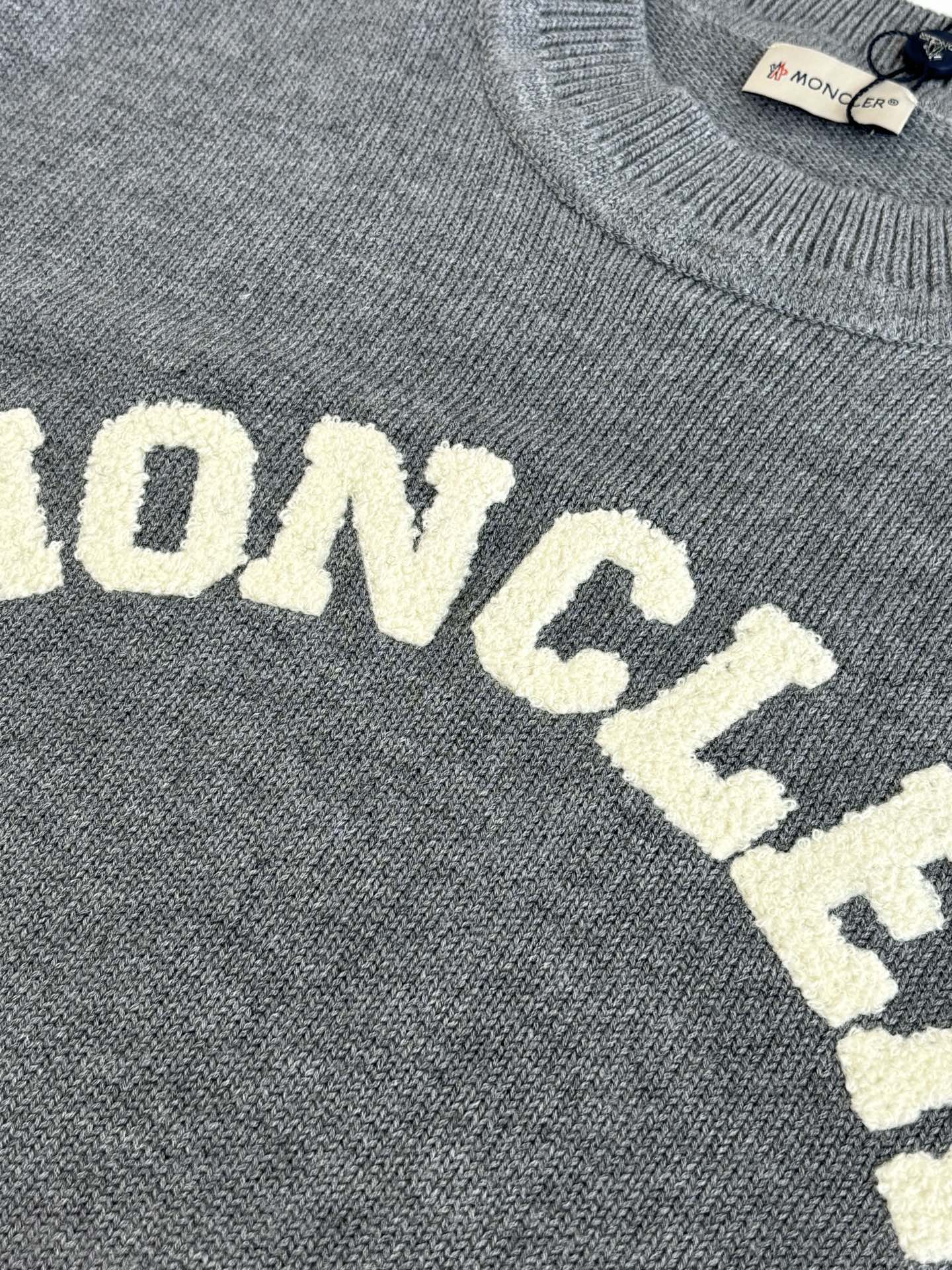 Grey knit sweater showing MONCLER lettering detail