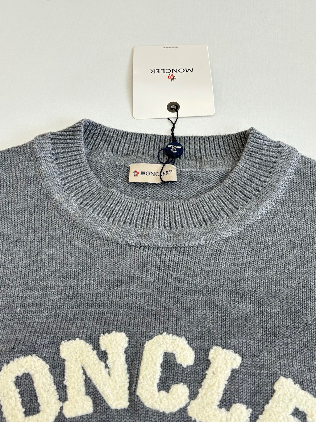 Grey crewneck sweater with MONCLER lettering across the chest