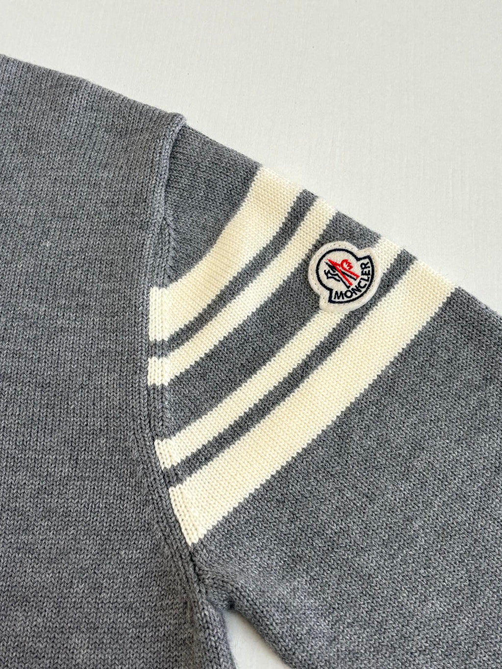 Grey sweater sleeve with striped armband and Moncler logo patch
