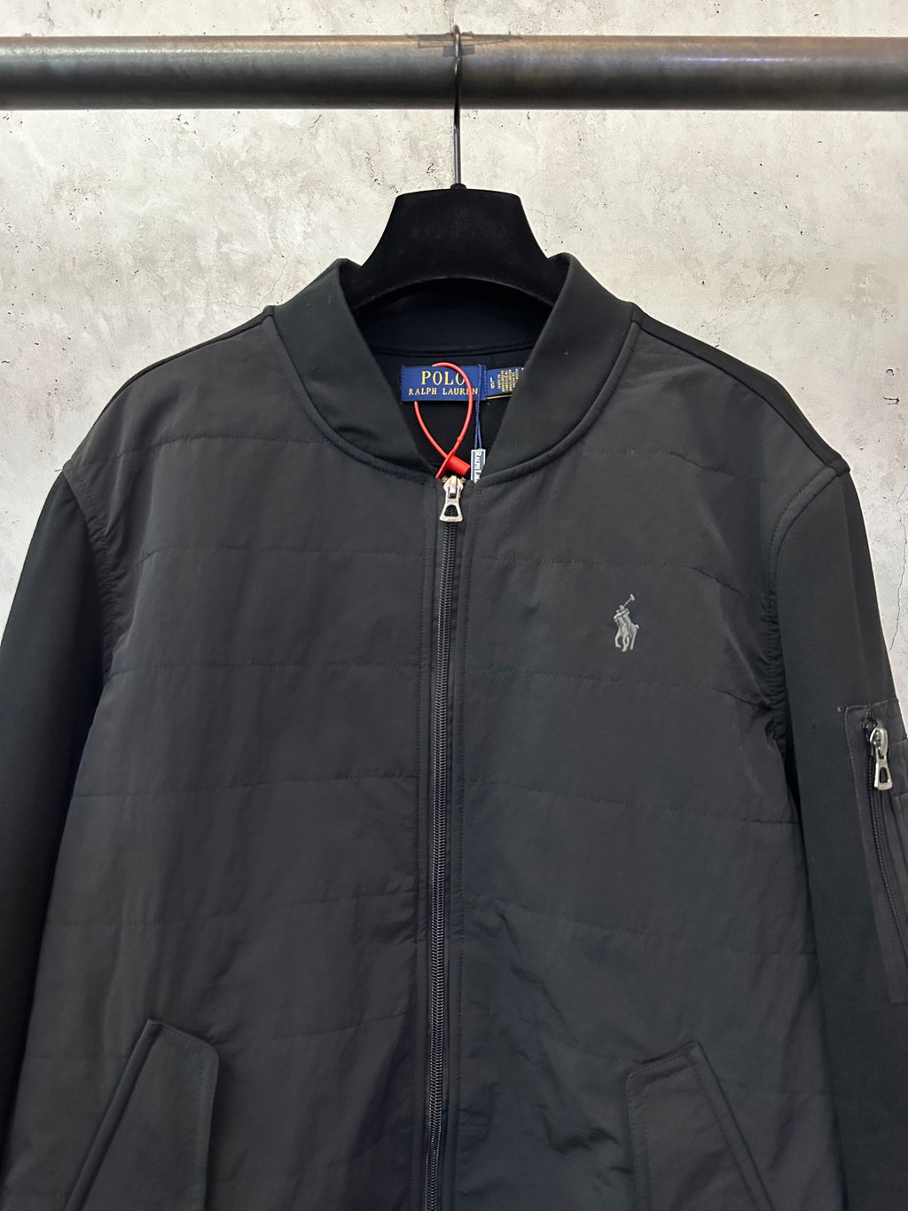 Black zip-up bomber jacket with chest logo embroidery and full front zipper.