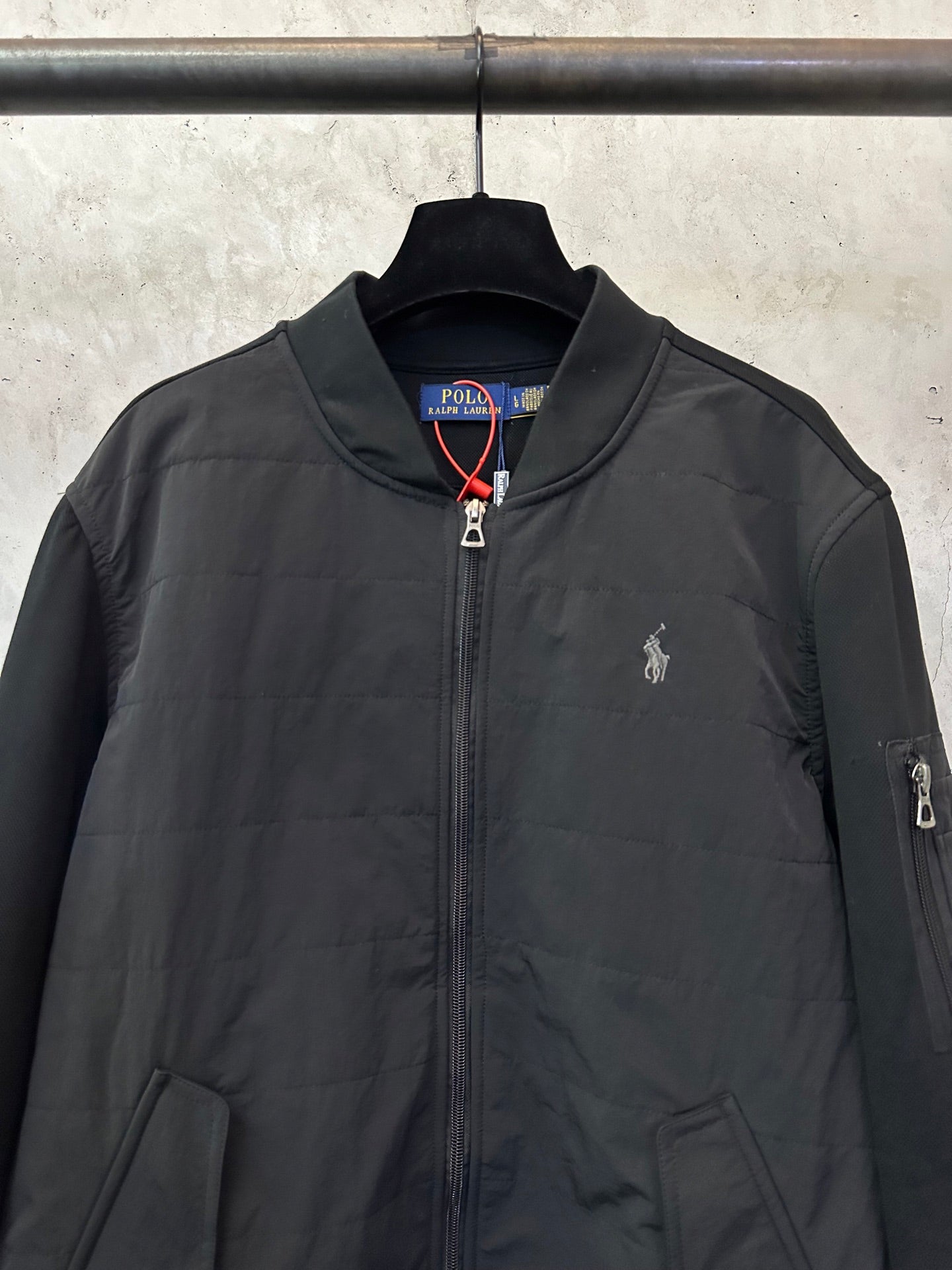 Black zip-up bomber jacket with chest logo embroidery and full front zipper.