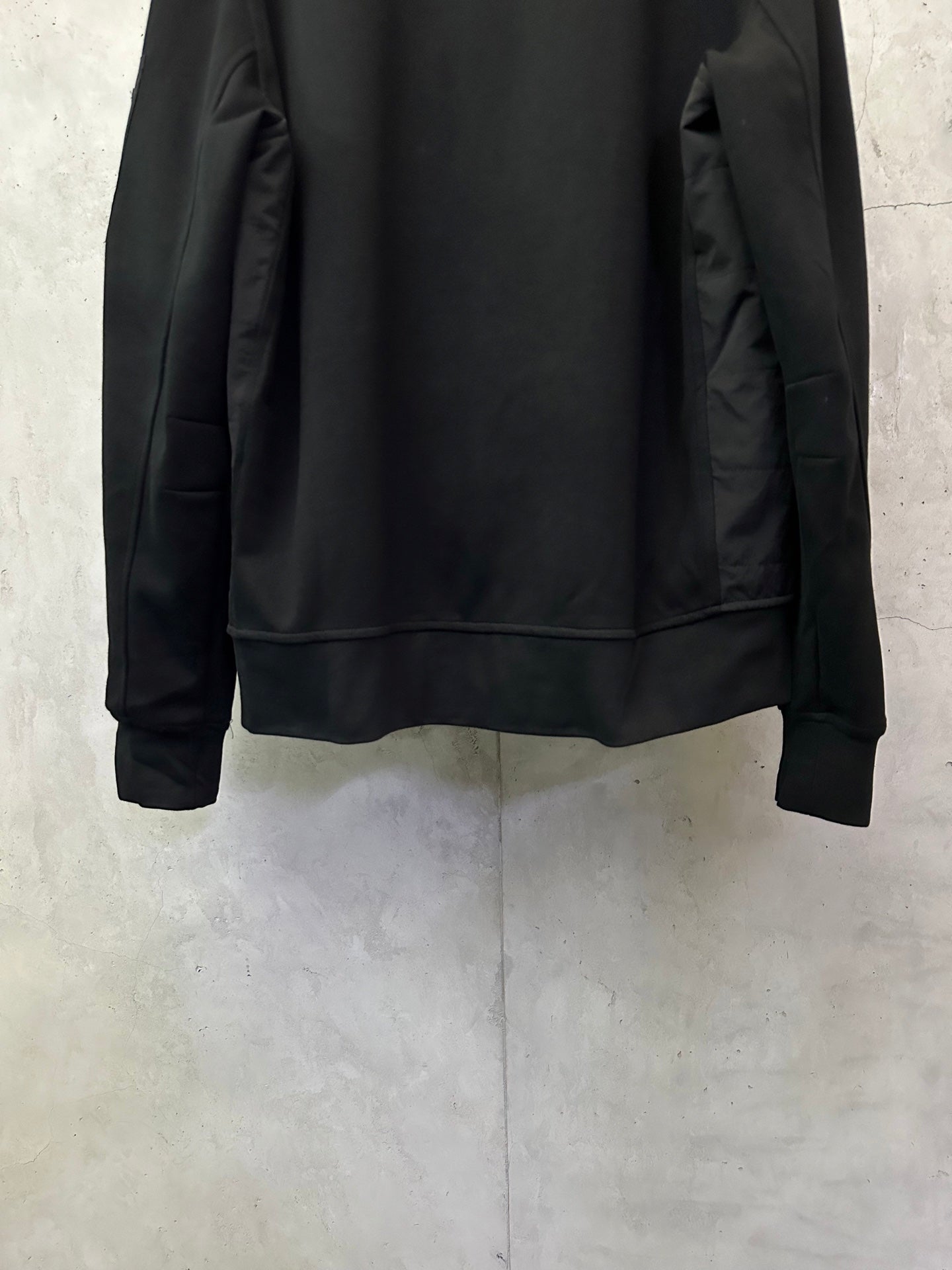 Black zip-up jacket back with ribbed waistband and full-length sleeves.