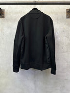 Black zip-up jacket with stand collar, full back view, ribbed hem at bottom.