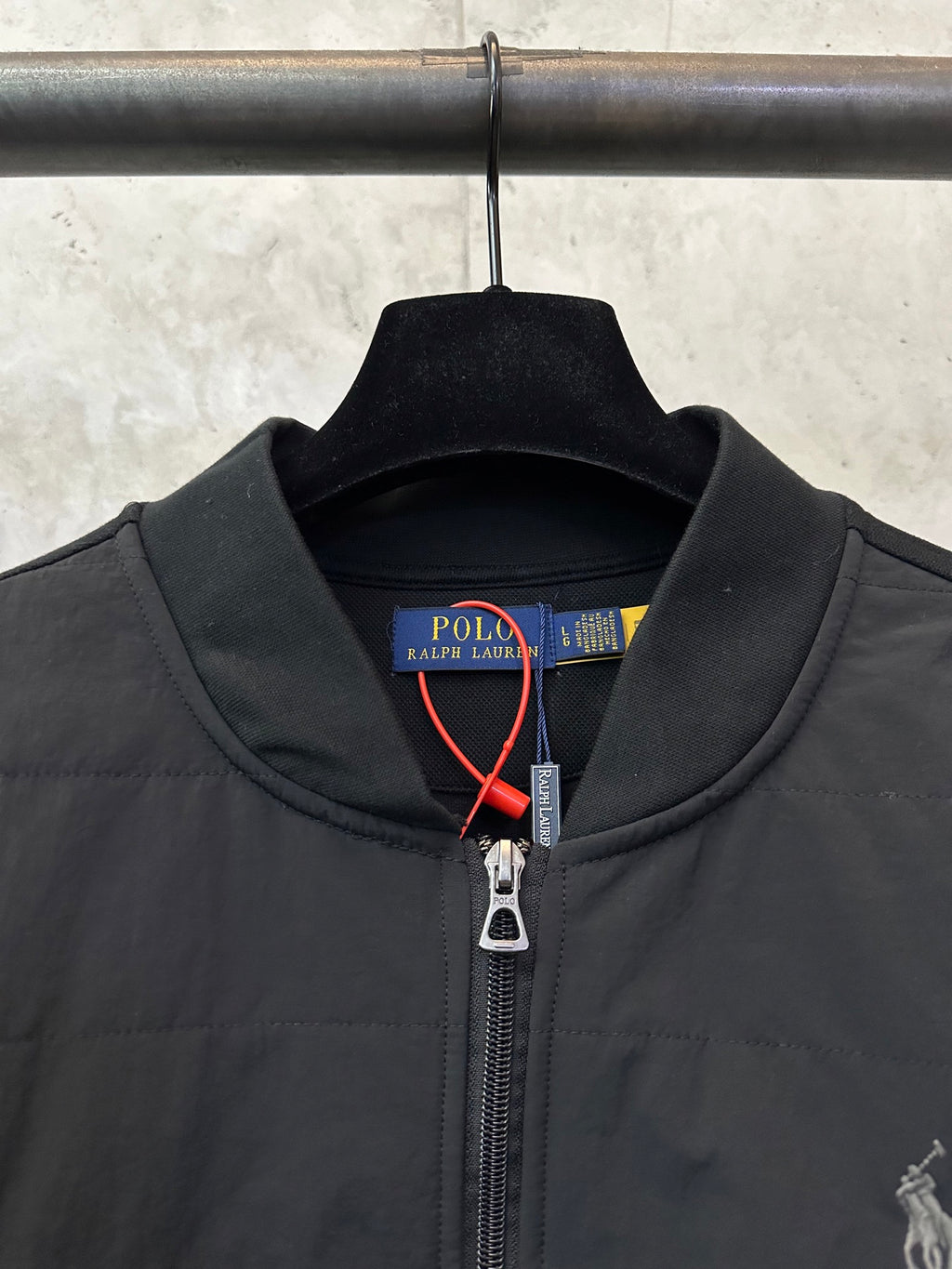 Black jacket collar with Polo Ralph Lauren label and metal zipper pull.