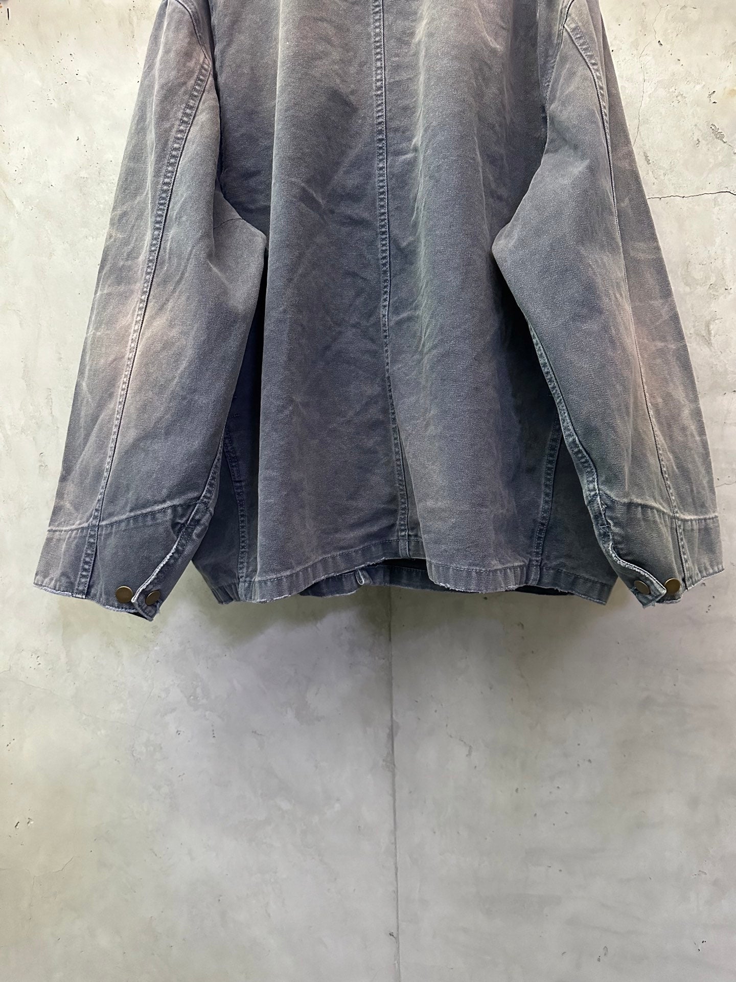 Long denim jacket back view in dark blue-gray with full sleeves and button placket