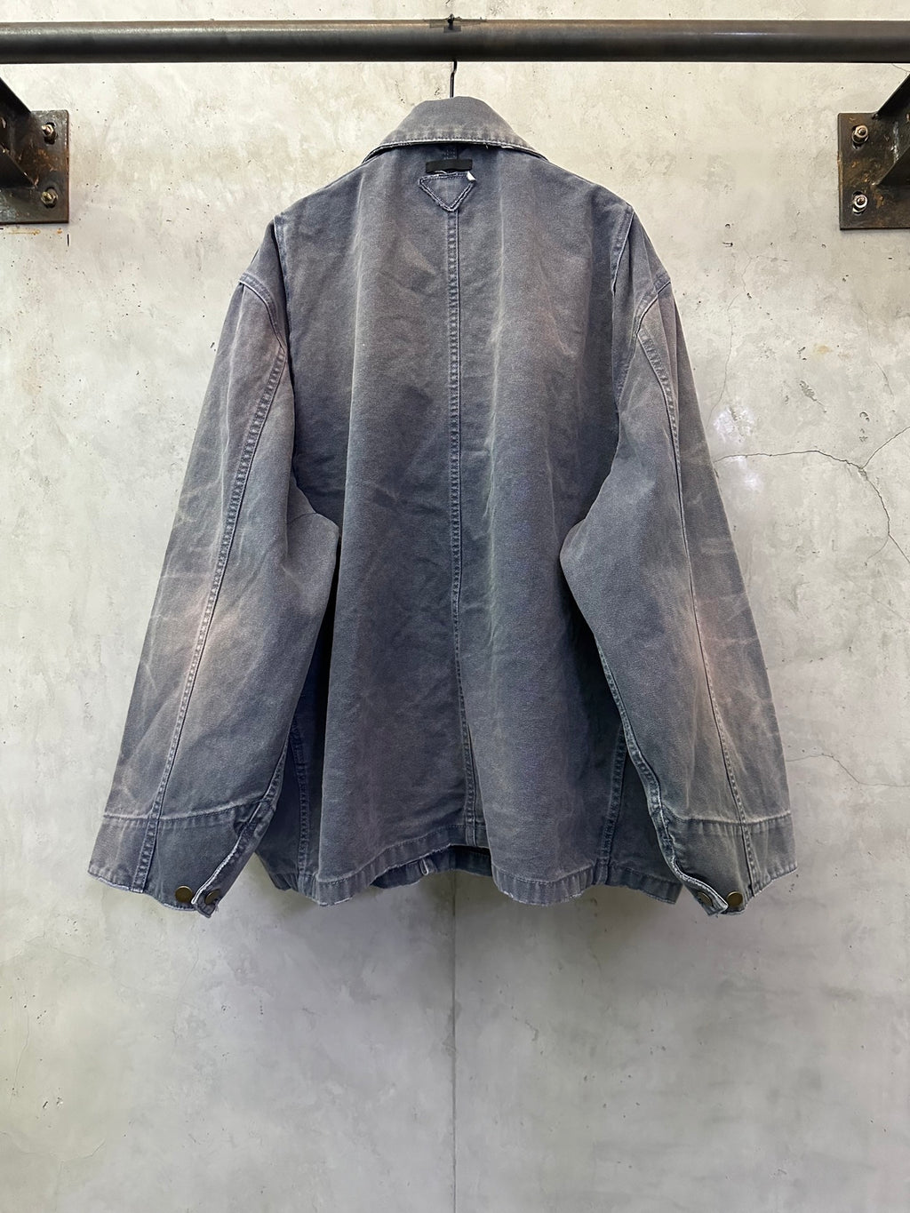 Back view of long denim jacket in dark blue-gray with seam details