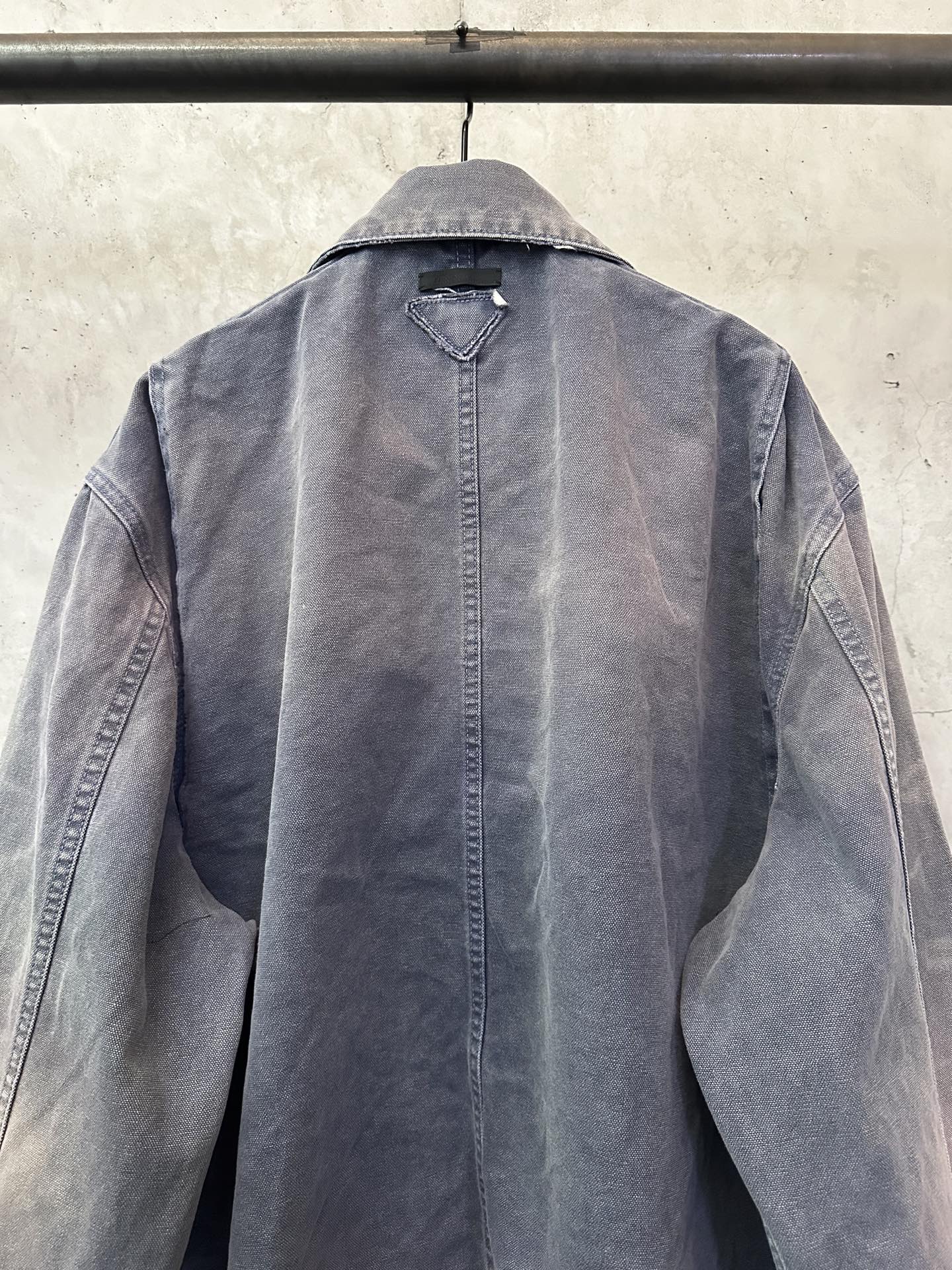 Long denim jacket back view with raised collar and central button placket