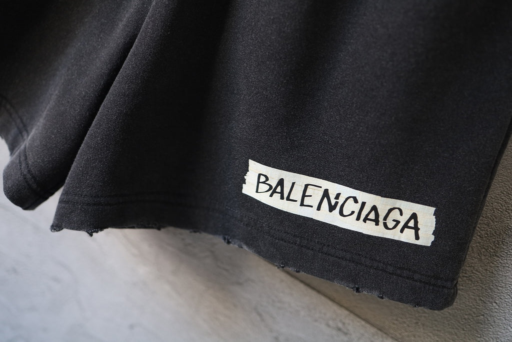 Balenciaga dark shorts with BALENCIAGA logo patch near the hem