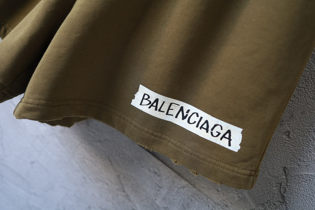 Olive shorts with Balenciaga logo patch on the hem
