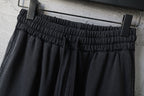 Black wide-leg pants with elastic waistband and inner hang tag