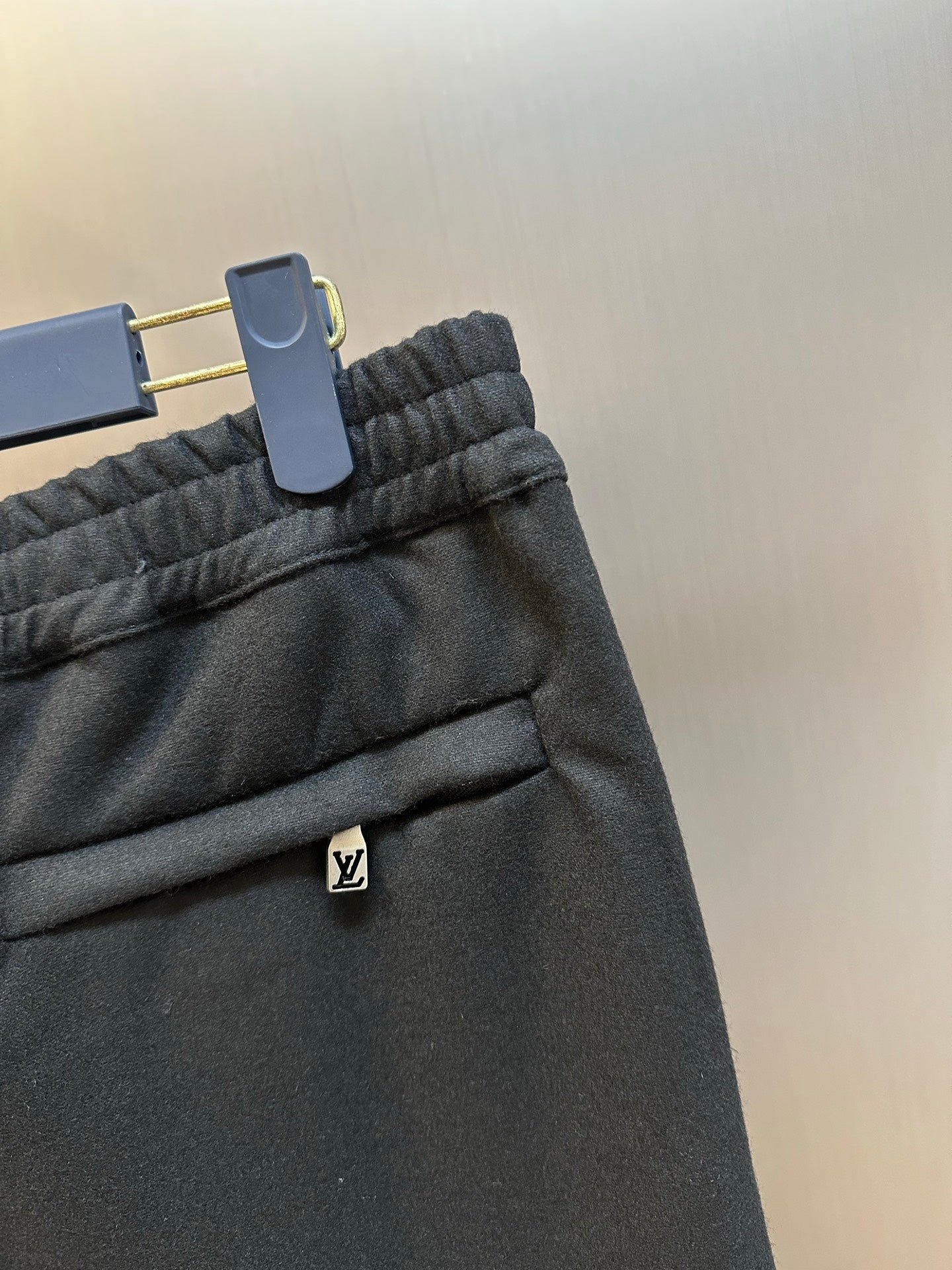 Louis Vuitton dark pants close-up of elastic waistband and LV logo patch
