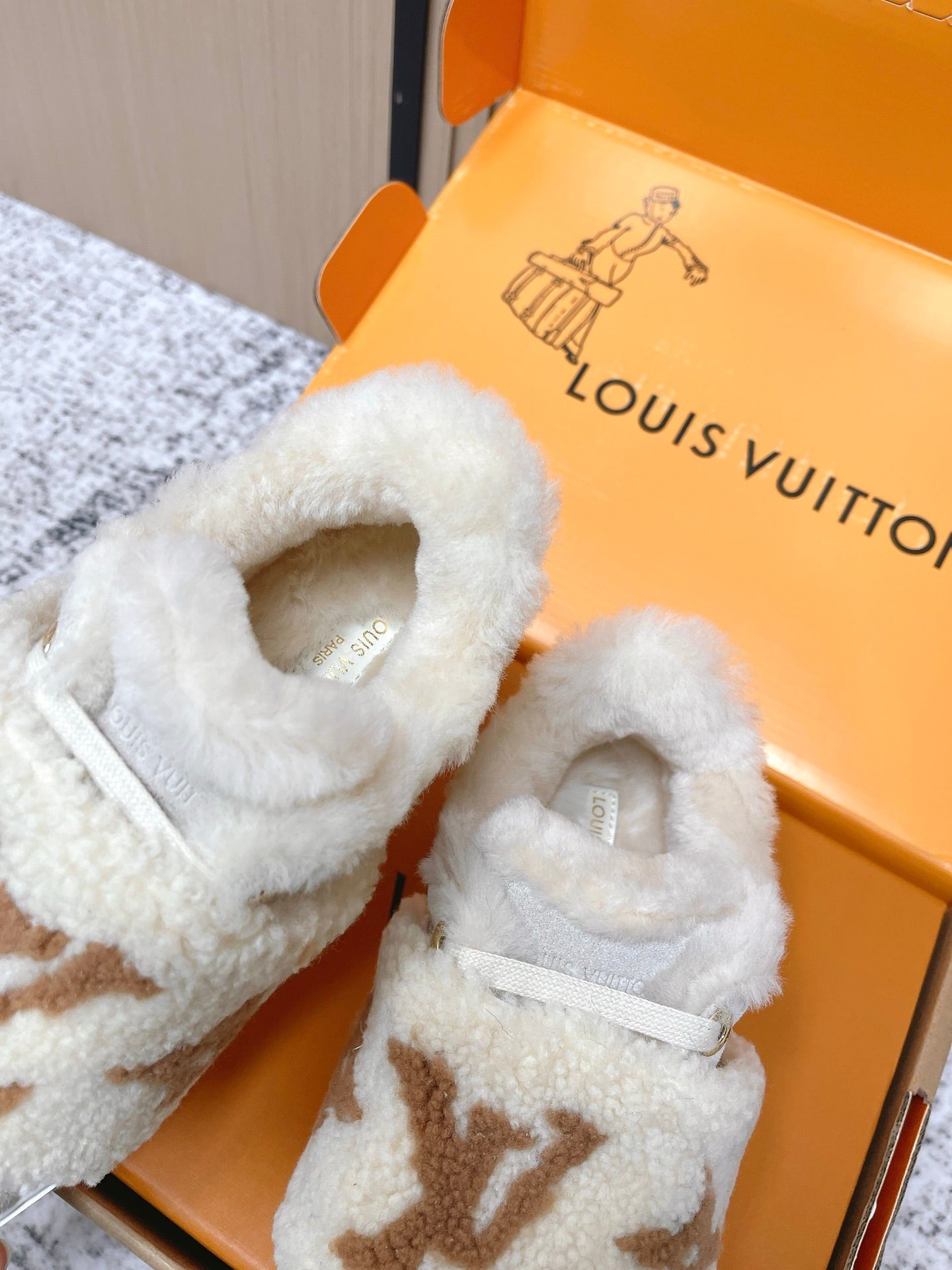 Shearling slip-on sneakers, close-up of light gray fur lining and tan monogram