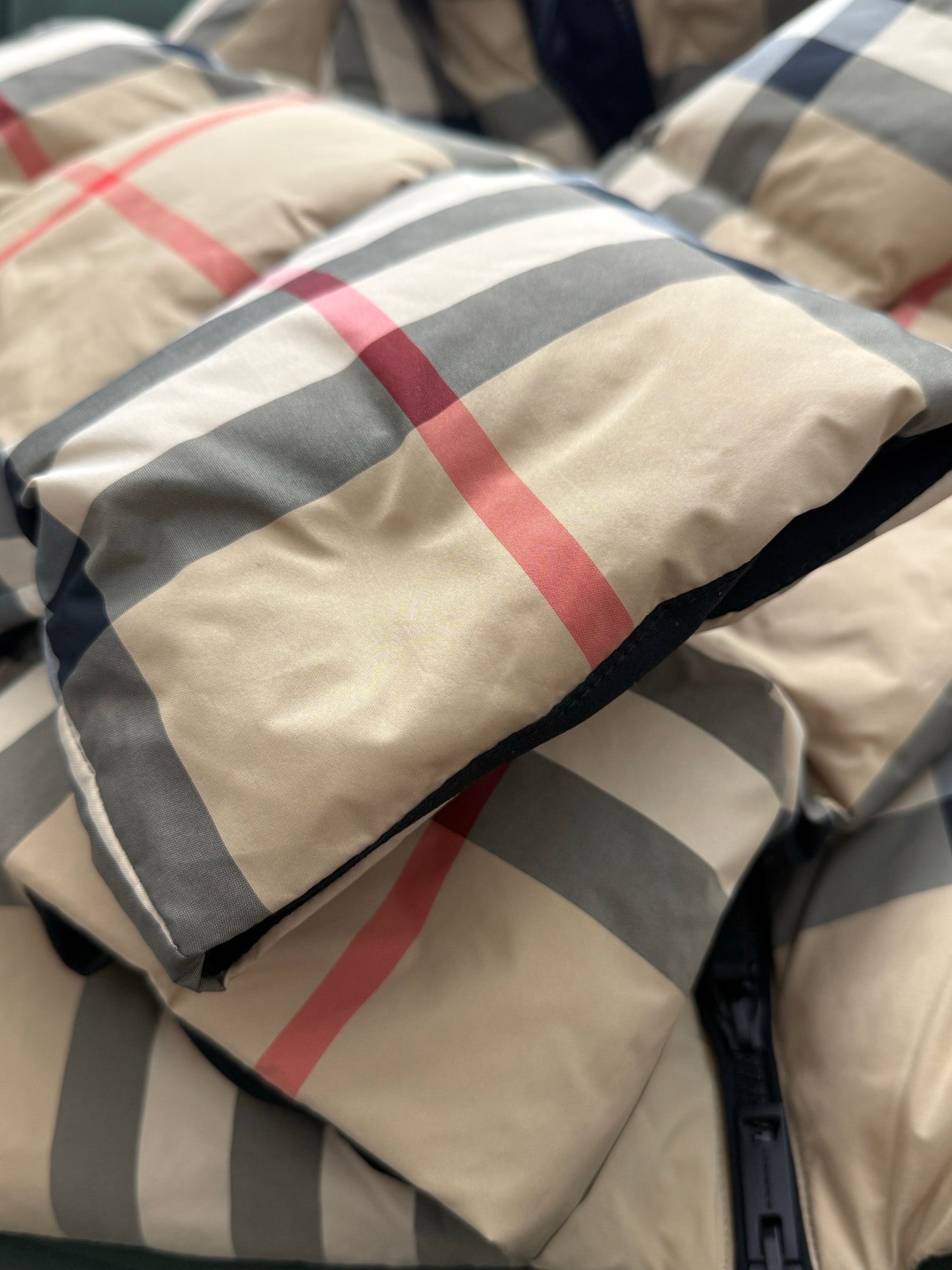 Burberry check puffer jacket fabric close-up with beige, gray, red, and navy stripes