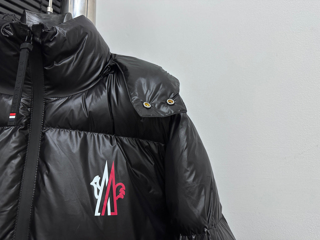 Black puffer jacket shoulder detail with snap button badge and chest logo