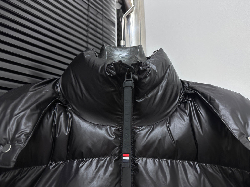 Black long puffer jacket with high collar and center zipper, snap hood detail