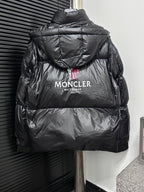 Black long puffer jacket back view with hood, “MONCLER” logo and text