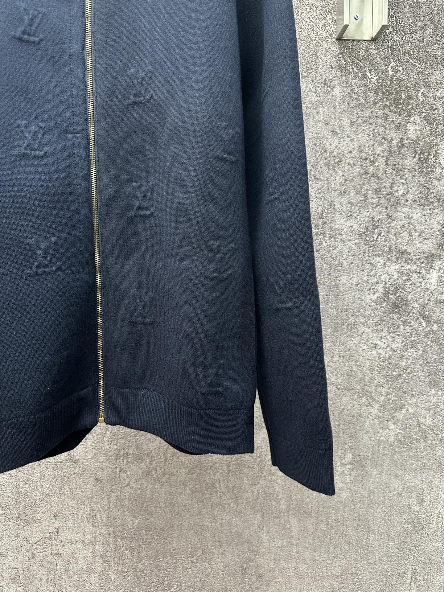 Dark blue long-sleeve zip jacket side view with gold zipper and ribbed hem