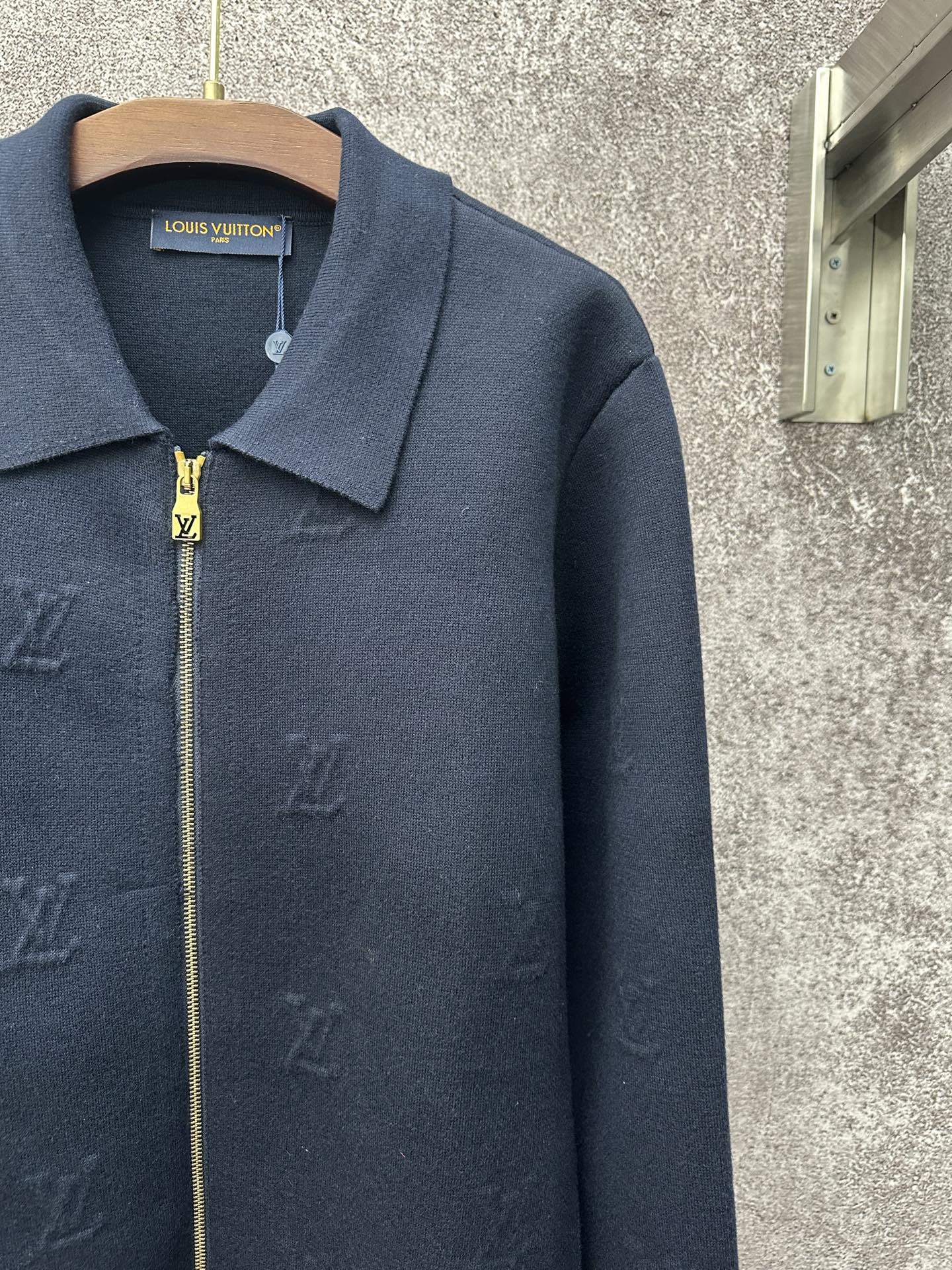 Dark blue long-sleeve zip jacket detail with gold zipper and pointed collar