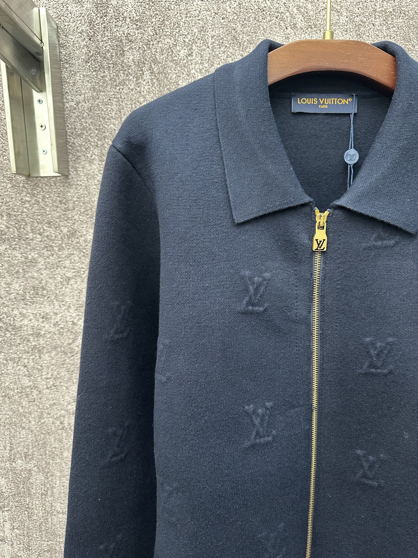 Dark blue long-sleeve zip jacket with pointed collar and subtle monogram pattern