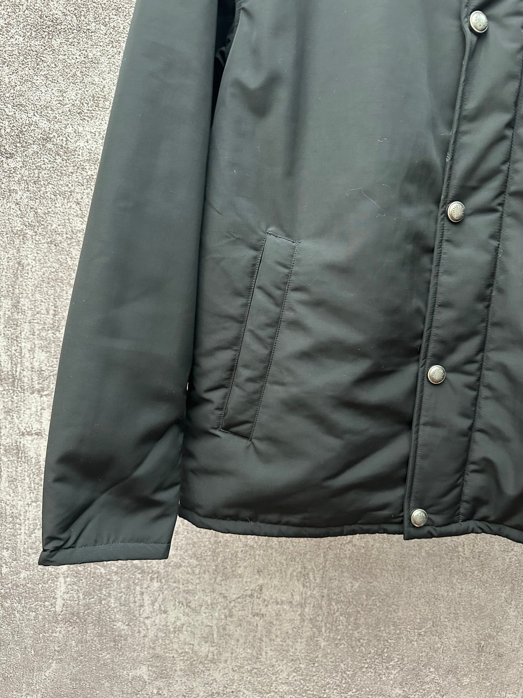 Long puffer jacket side view, dark green with ribbed hem and button placket