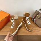 Hermes unisex suede sneakers, white laces and tan shearling collar, held up for view