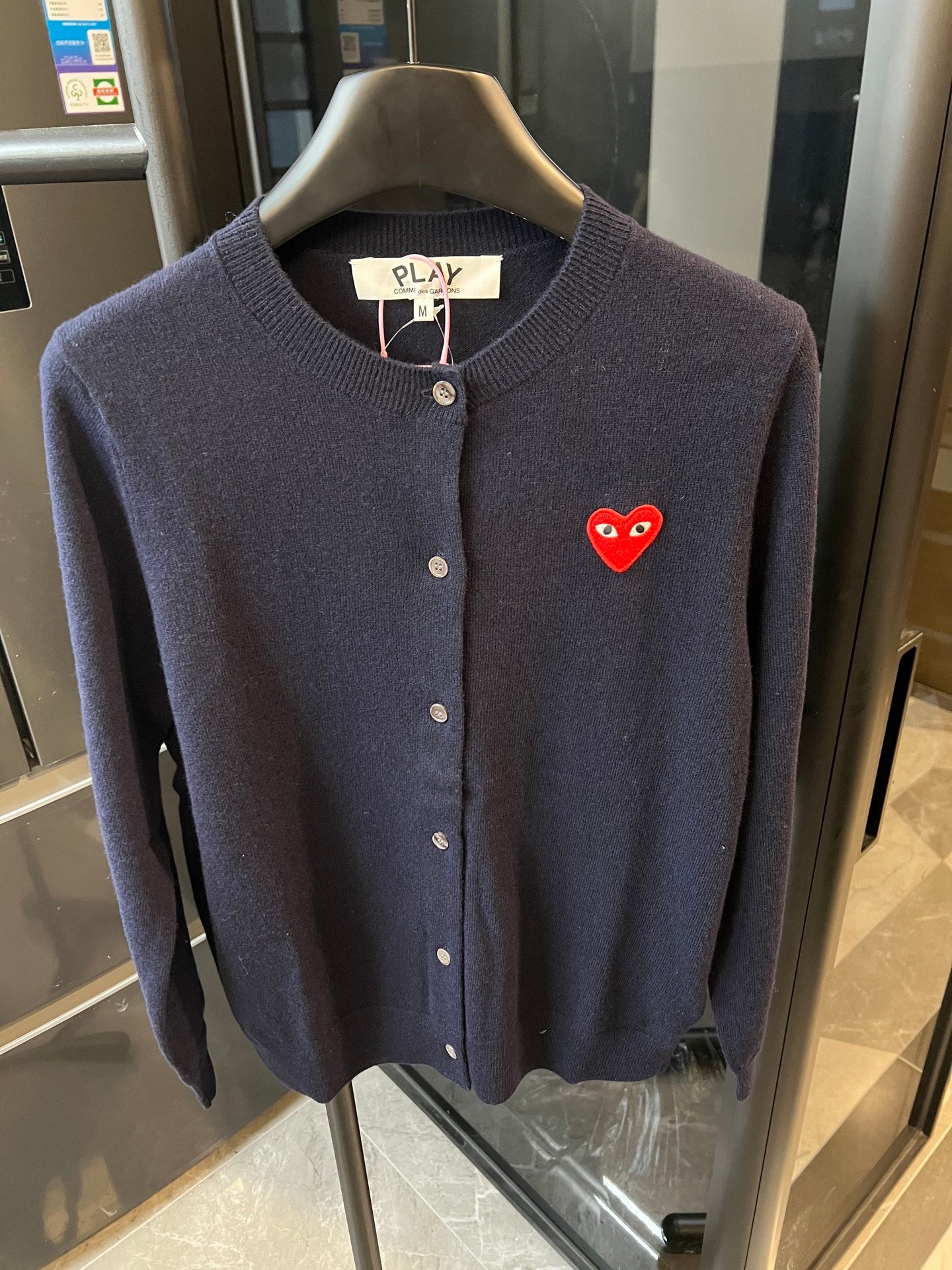 Dark navy knit cardigan with button front and red heart patch on the left chest