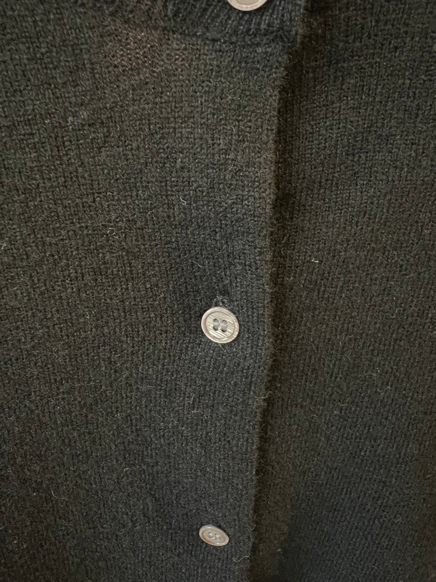 Amiri dark knit cardigan button placket with small metal buttons.
