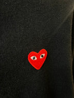 Embroidered red heart logo patch on Amiri dark knit cardigan.