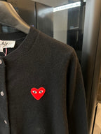 Amiri dark knit cardigan with embroidered red heart logo patch on chest.