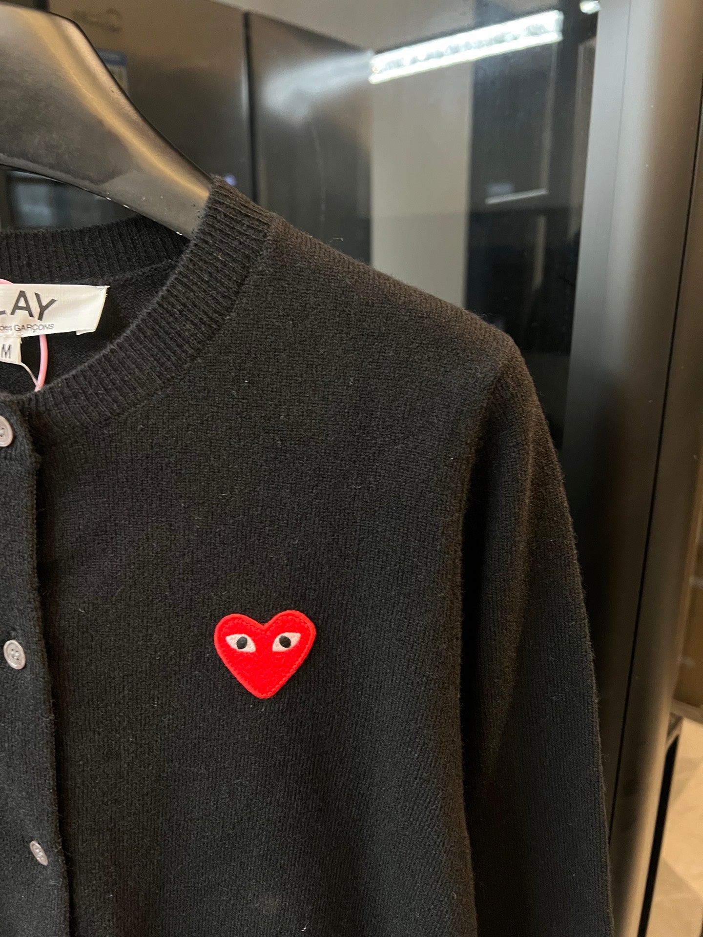 Amiri dark knit cardigan with embroidered red heart logo patch on chest.