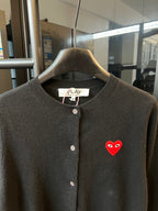 Amiri dark knit cardigan with round neckline, buttons, and red heart logo patch.