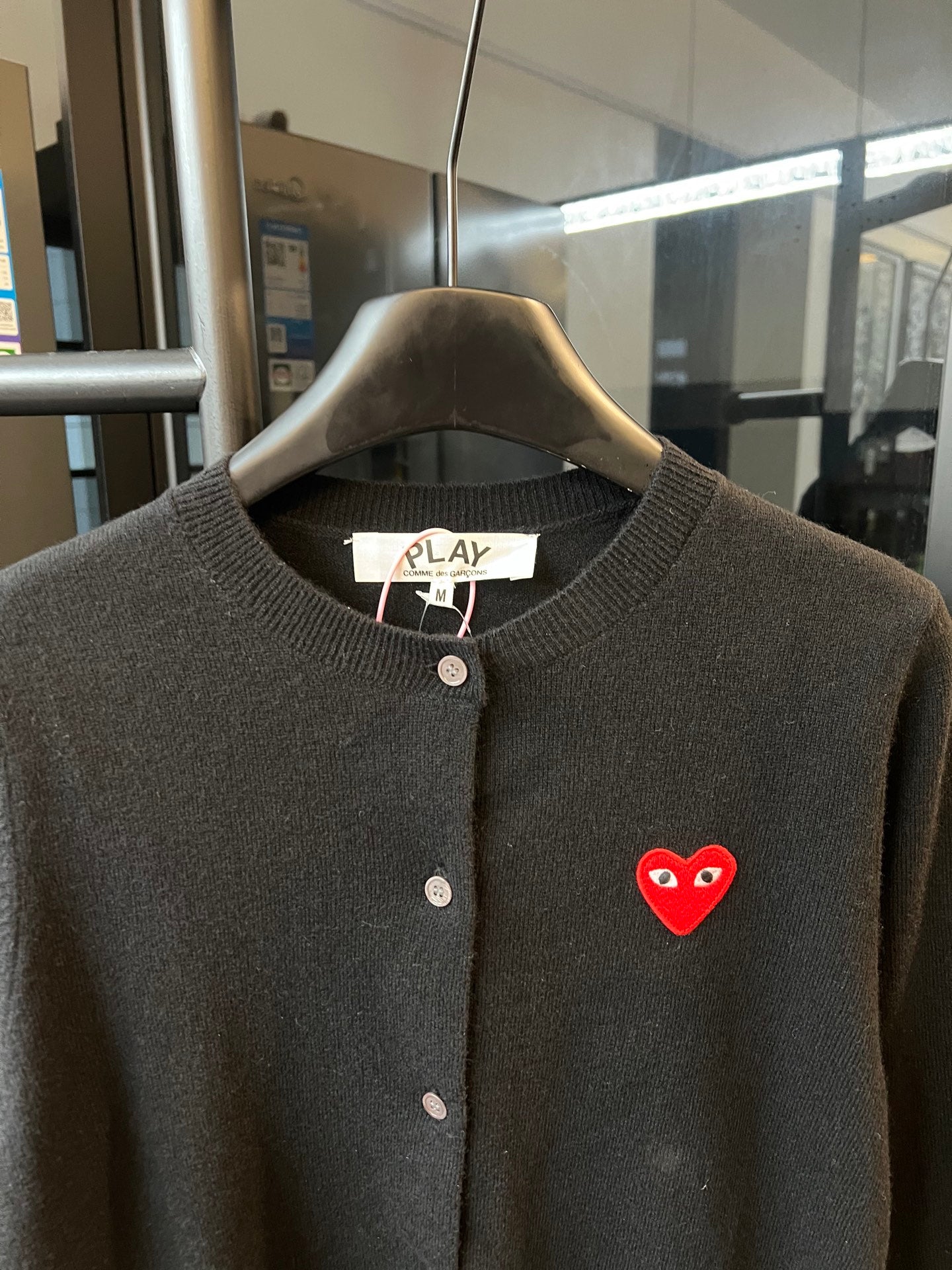 Amiri dark knit cardigan with round neckline, buttons, and red heart logo patch.