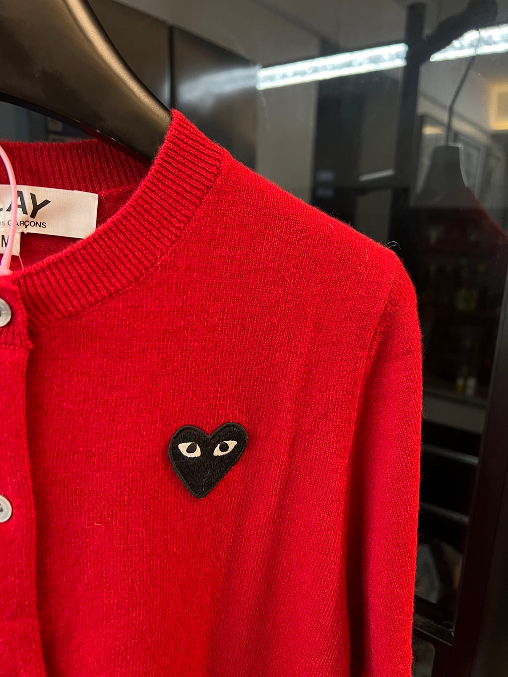 Red knit cardigan shoulder with black cat-face heart applique and ribbed neckline