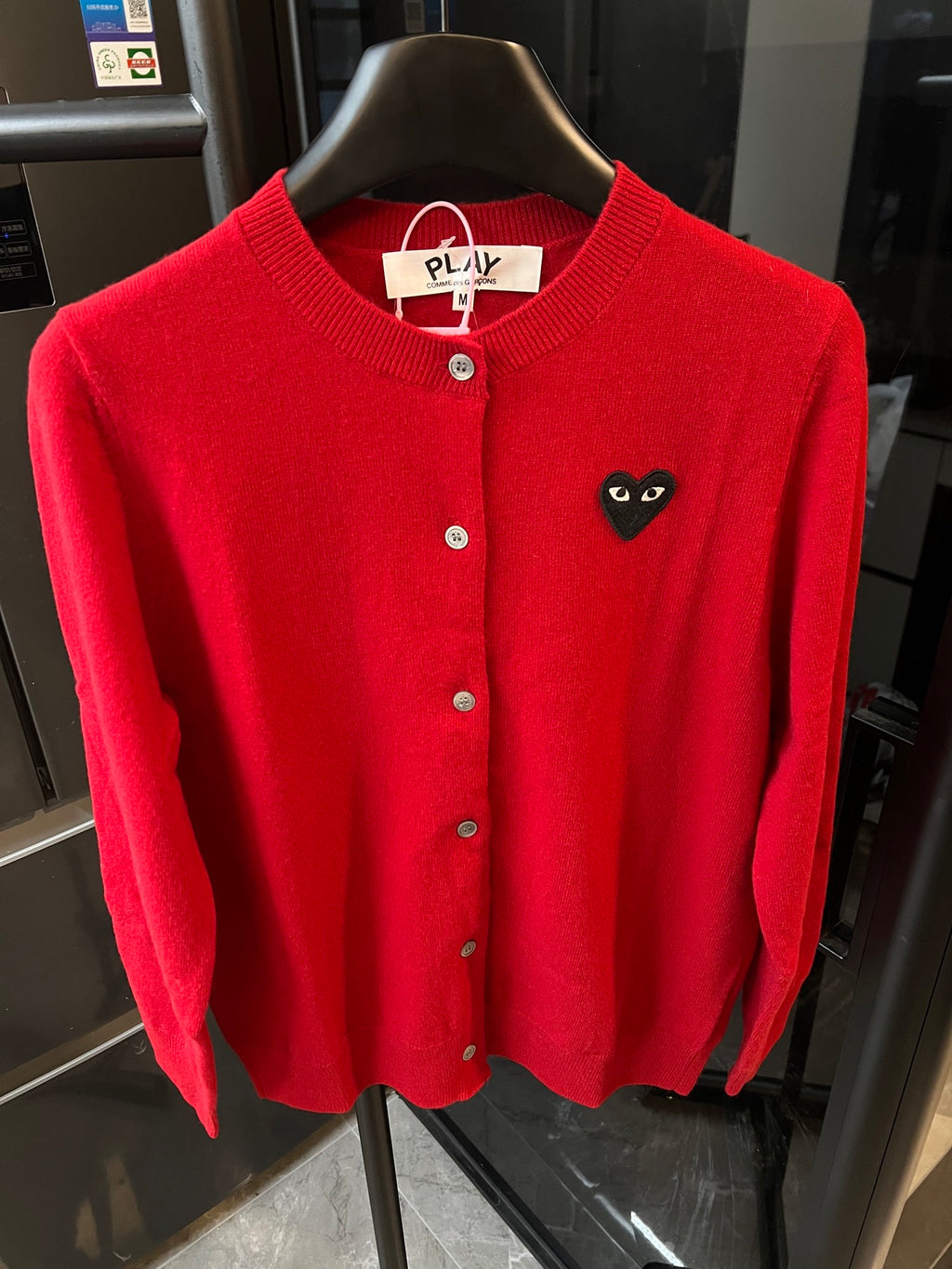 Red knit cardigan with round collar, front buttons, and black cat-face heart applique