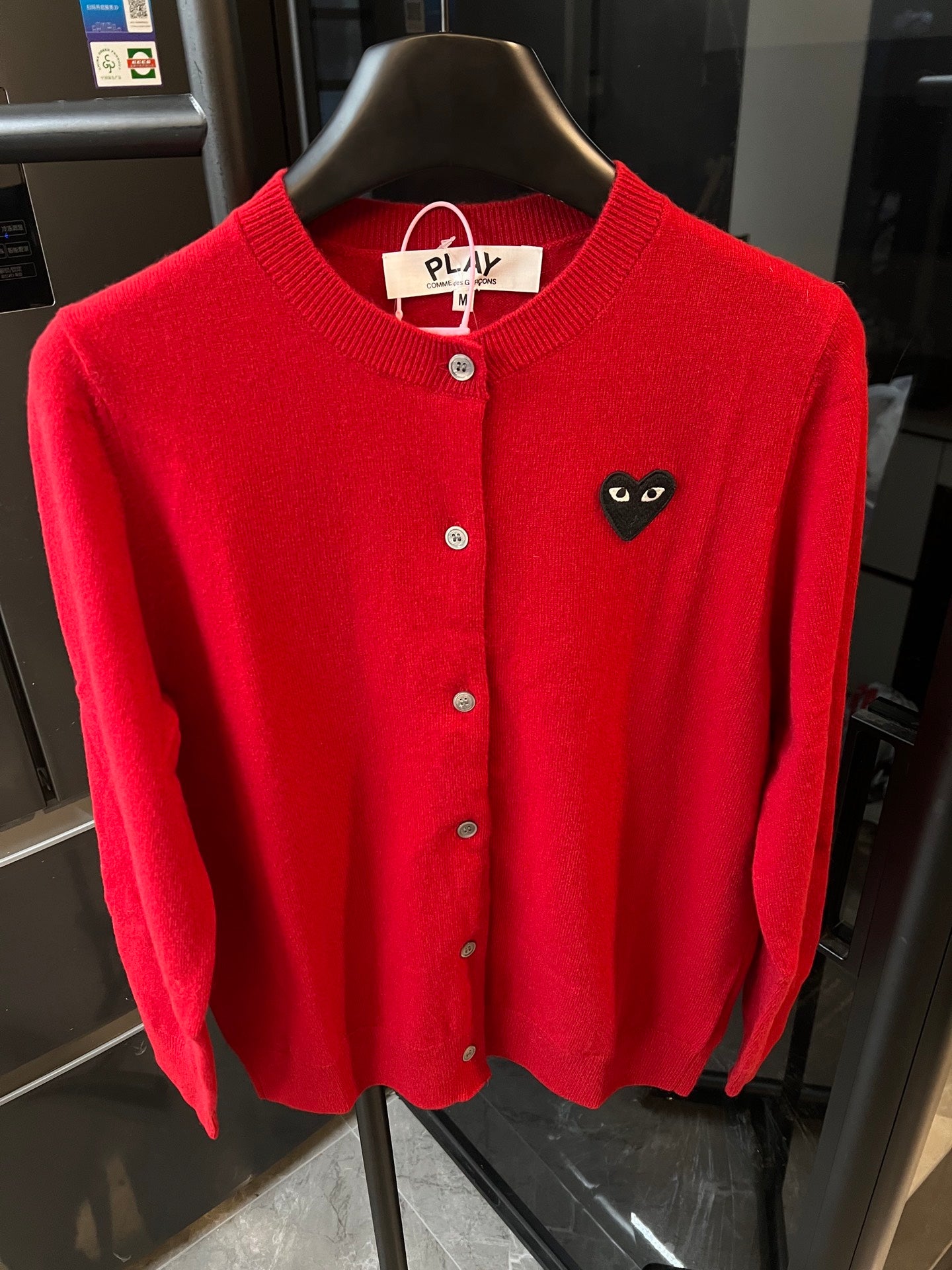 Red knit cardigan with round collar, front buttons, and black cat-face heart applique