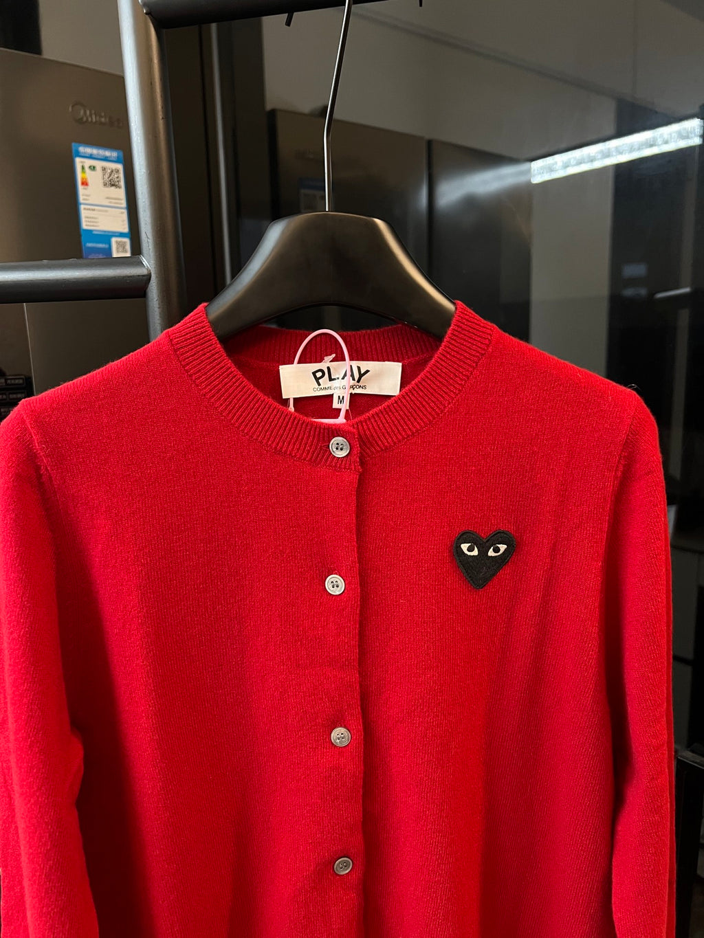 Red knit cardigan with black cat-face heart applique on the left chest and button front