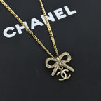 Gold-tone bow pendant necklace, close-up with ornate charm detail