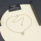 Gold-tone chain necklace with bow pendant, laid out with authenticity card