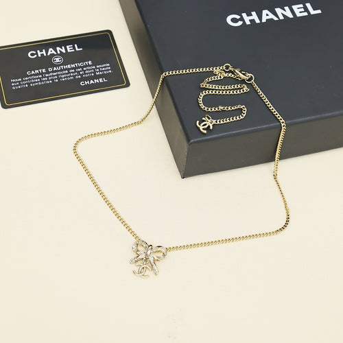 Gold-tone chain necklace with bow pendant, shown with black gift box