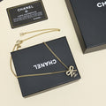 Gold-tone chain necklace with bow charm, shown on black gift box