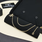 Gold-tone layered chain necklace with bow charms on black jewelry holder