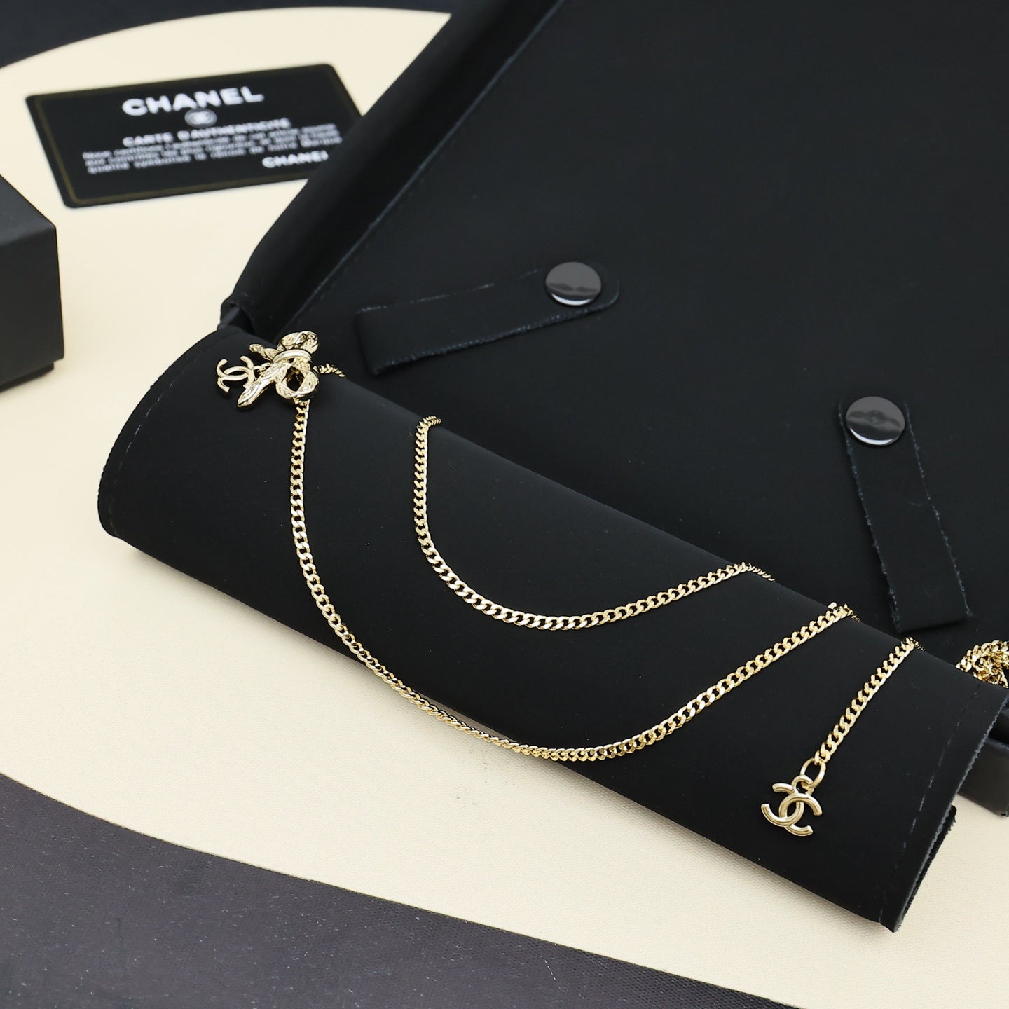 Gold-tone layered chain necklace with bow charms on black jewelry holder