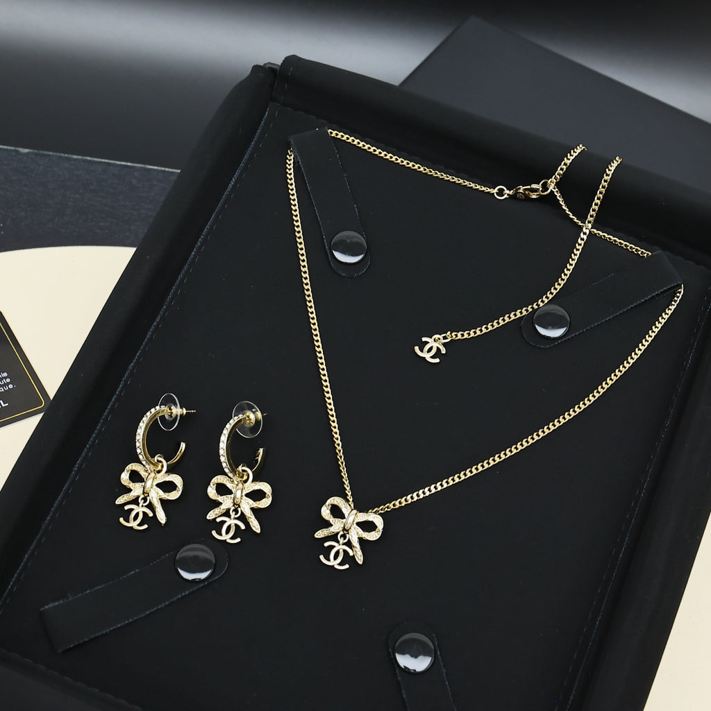 Gold-tone Chanel jewelry set with bow earrings and pendant necklace on black tray