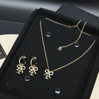 Gold-tone Chanel jewelry set with bow earrings and pendant necklace on black tray