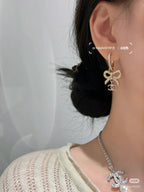 Gold-tone dangling earrings with bow Chanel charm and rhinestone hoop, side view