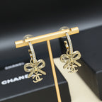 Gold-tone drop earrings with rhinestone hoop, bow charms hanging from bar display