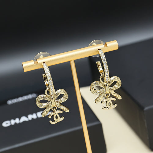 Gold-tone drop earrings with rhinestone hoop, bow charms hanging from bar display
