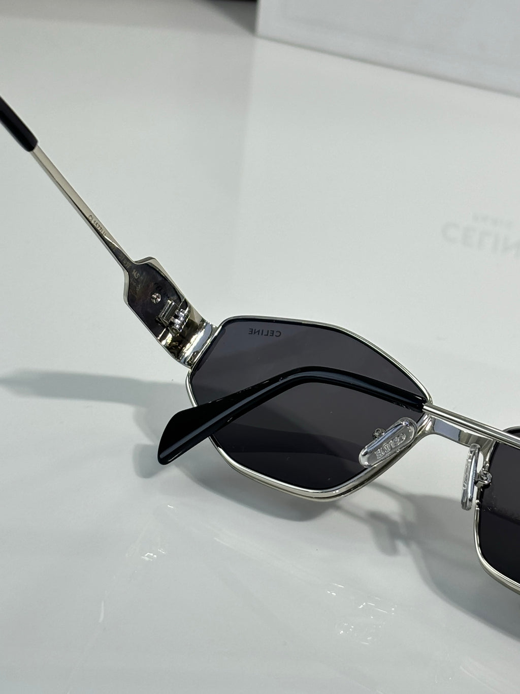 Metal sunglasses with dark lenses and clear nose pads, close-up view