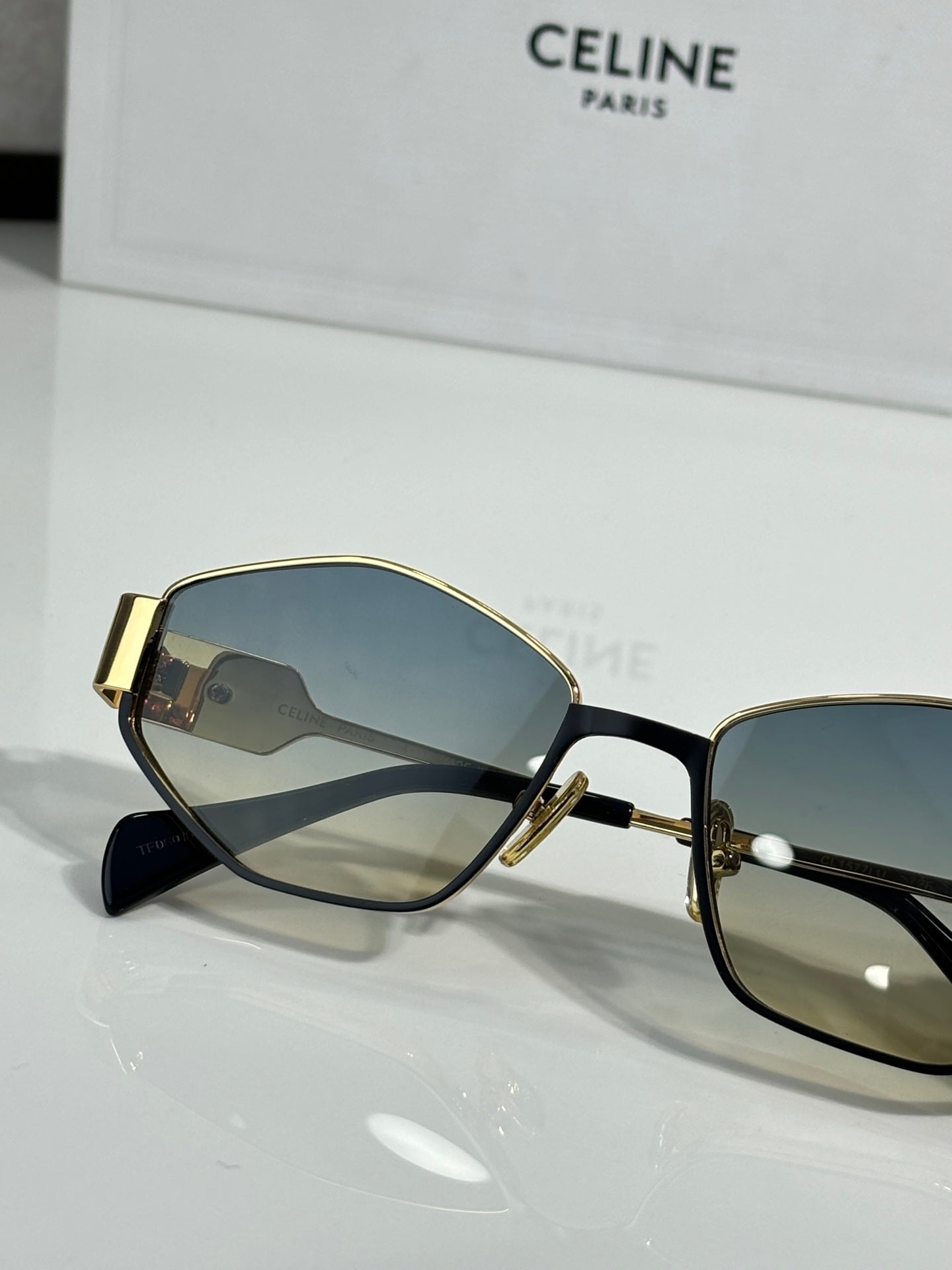 Gold-trim sunglasses with blue lenses and black temples, close-up side view